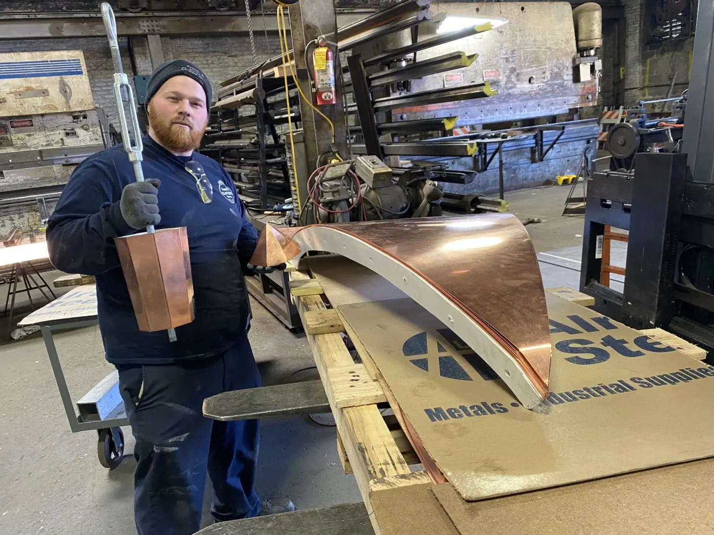 Fabricator holding a formed copper part on the shop floor
